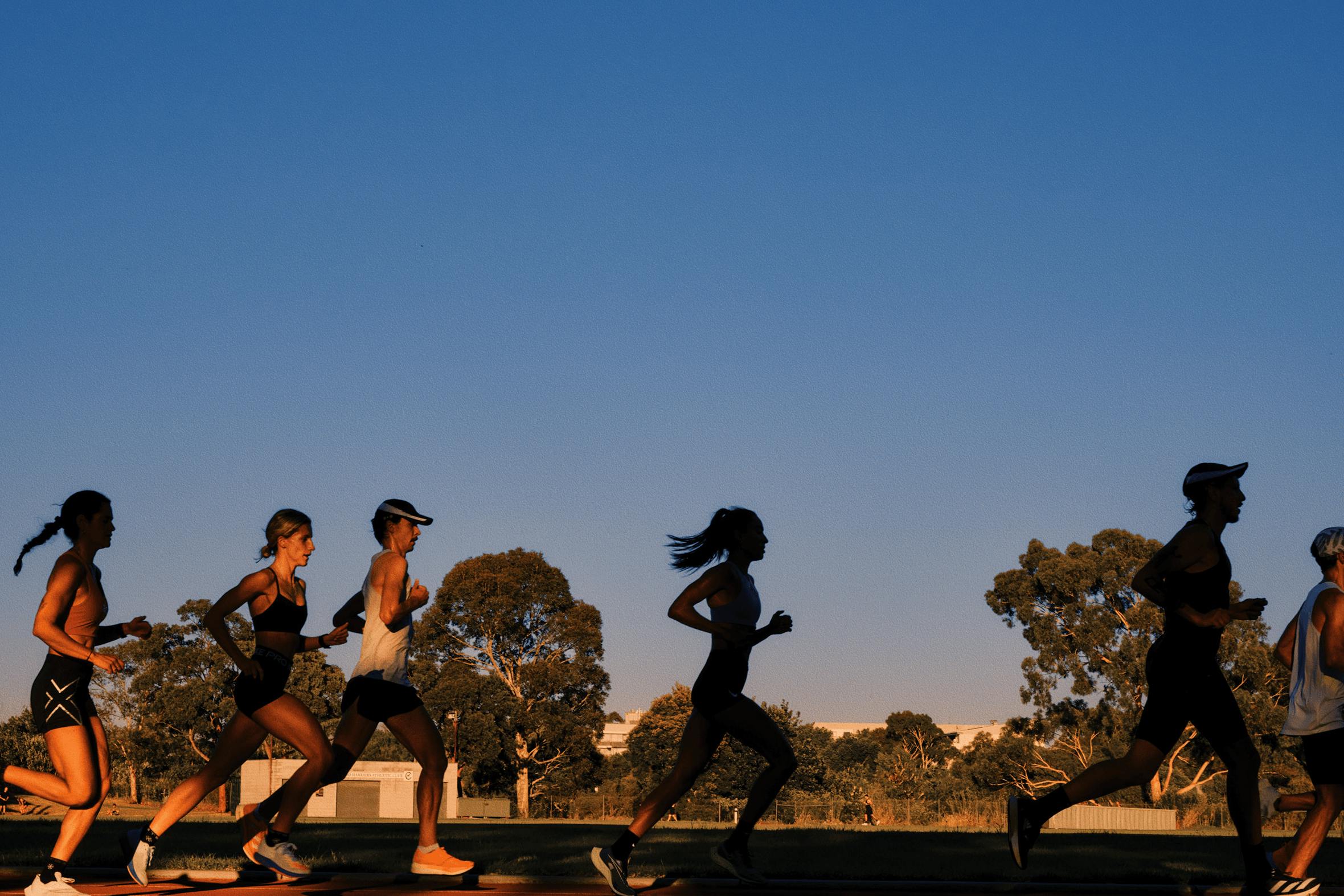 A group of people running around a track.